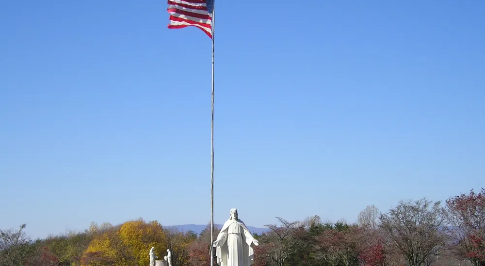 a flagpole with a statue in the middle of a park