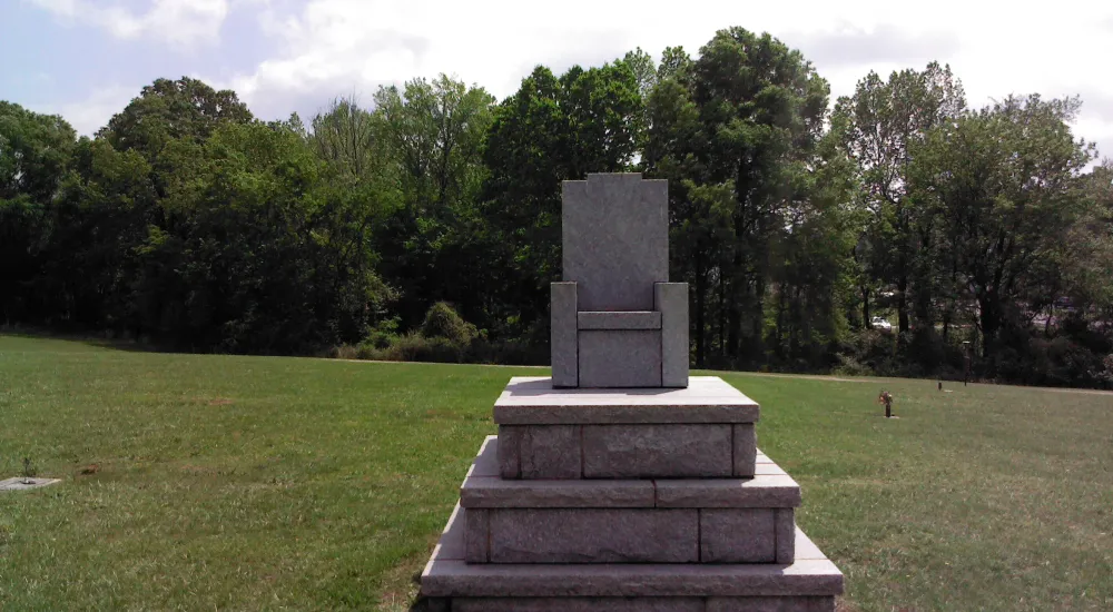 a stone statue in a grassy field