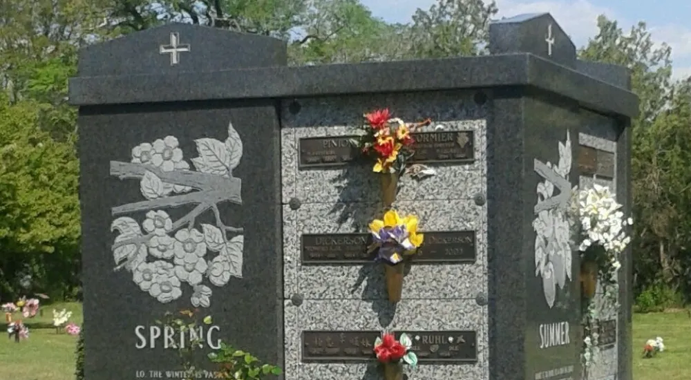 a tombstone with flowers and a cross