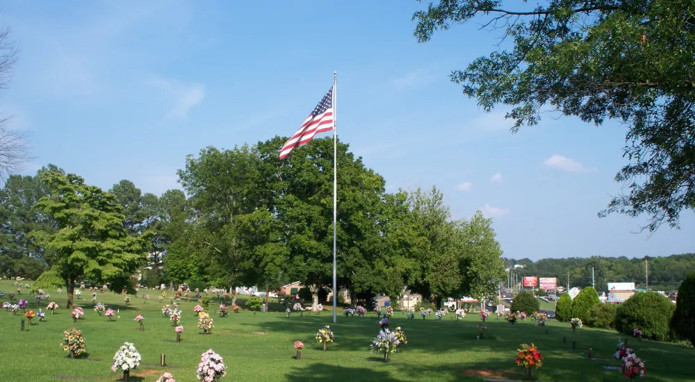 a flagpole with a flag on it in a park with people