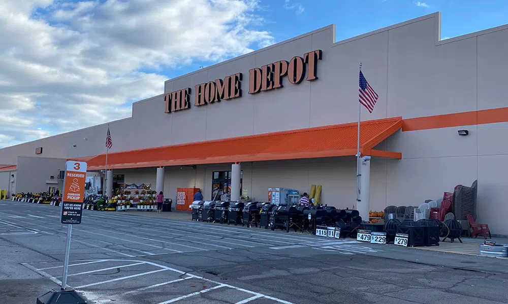 Front view of The Home Depot store with outdoor merchandise and reserved parking in a large parking lot.
