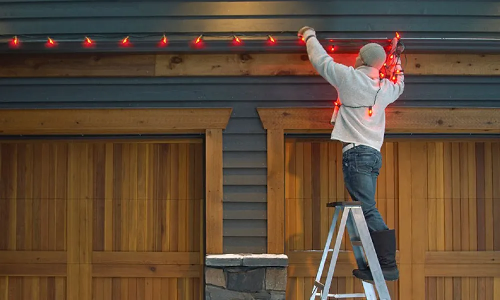 a person on a ladder hanging holiday lights
