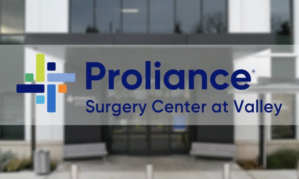 Proliance Surgery Center at Valley logo with colorful cross symbol over blurred medical building entrance.