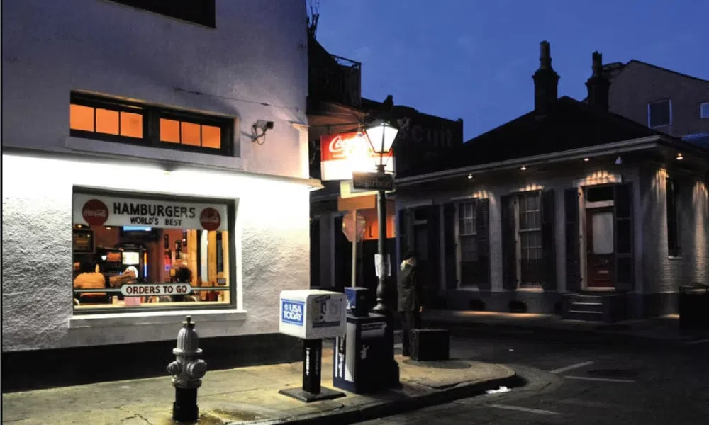 Night street scene with a brightly lit hamburger restaurant window and a nearby streetlamp illuminating the corner.