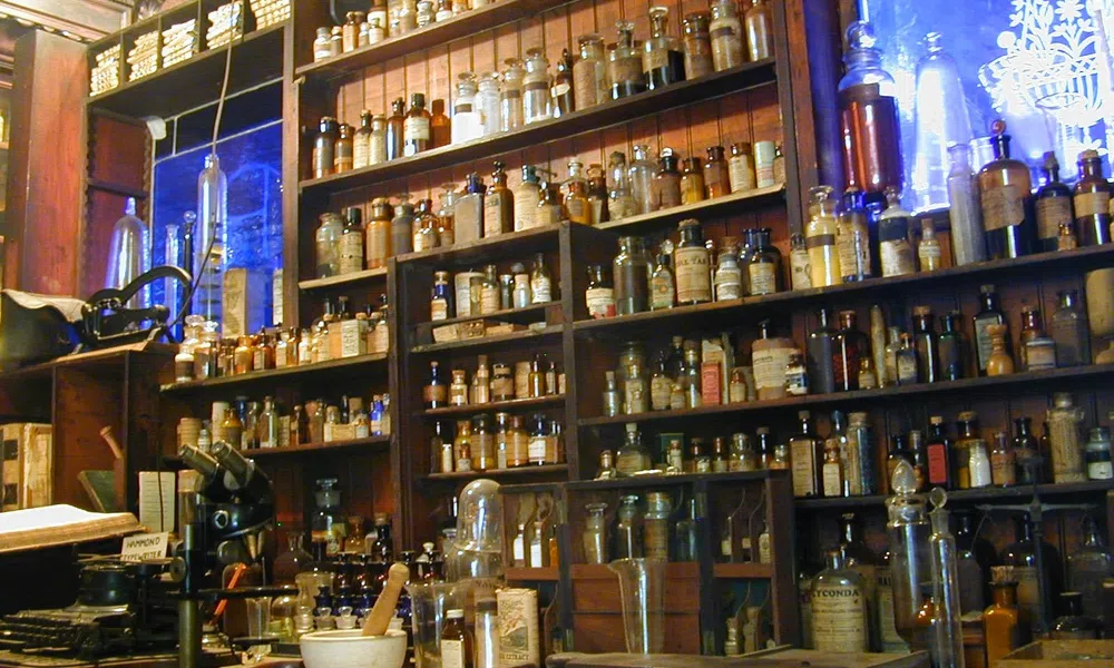 Shelves filled with vintage apothecary jars and bottles in an old-style pharmacy setting.