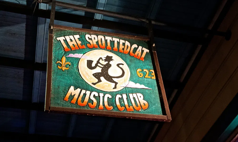 Wooden sign for The Spotted Cat Music Club with a silhouetted cat musician playing saxophone.