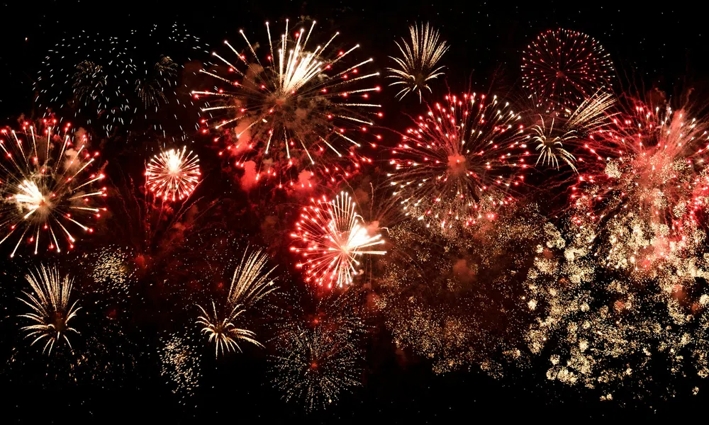 Bright red and gold fireworks bursting vividly against a dark night sky during celebration.