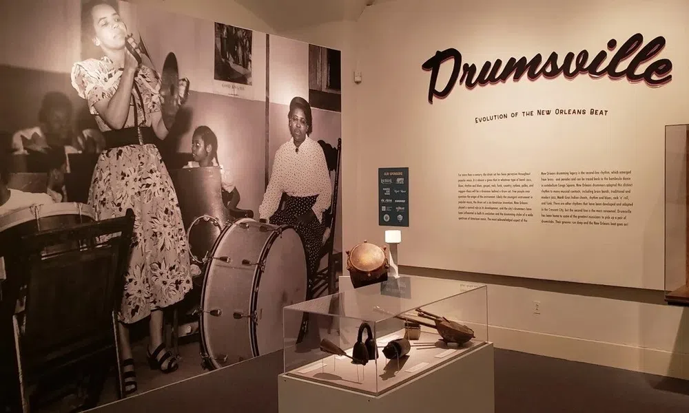 Exhibit showcasing the evolution of New Orleans beat with vintage jazz band photo and percussion instruments.