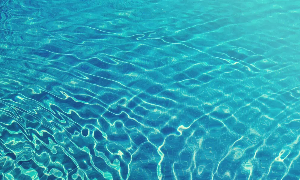 Clear blue water with ripples and light reflections creating abstract patterns on the surface.