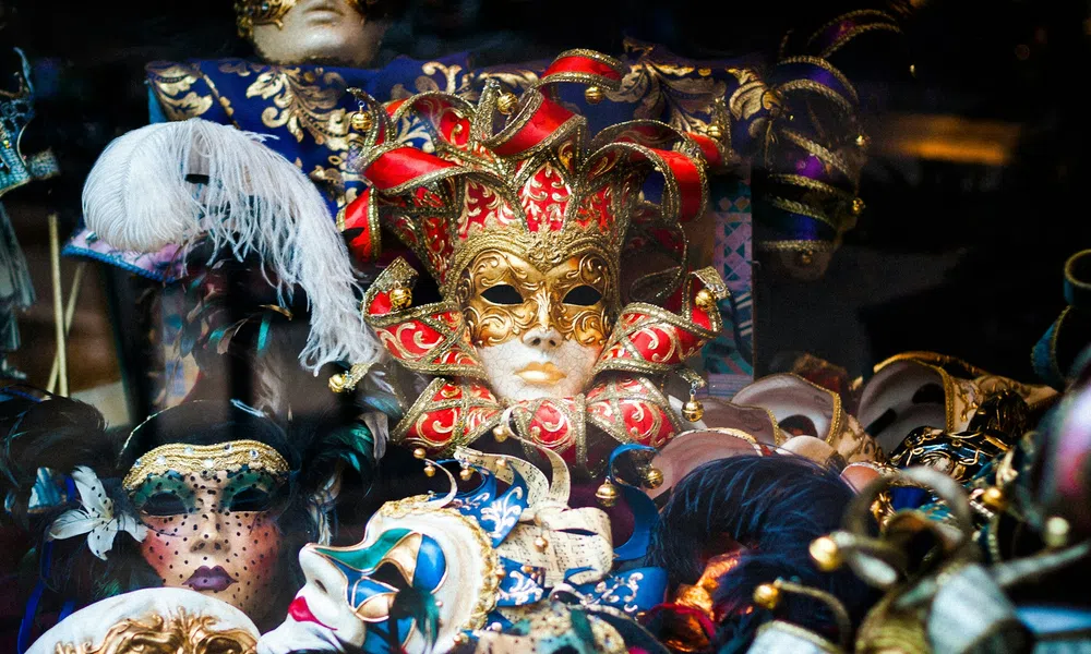 Colorful Venetian carnival masks with intricate designs, feathers, and gold accents on display