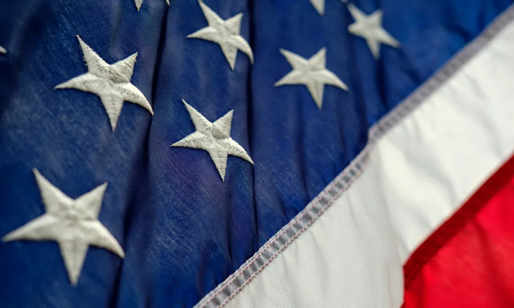 Close-up of the American flag showing embroidered white stars on blue and red and white stripes.