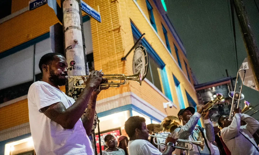 Street musicians playing trumpets and trombones during a lively outdoor jazz performance at night.