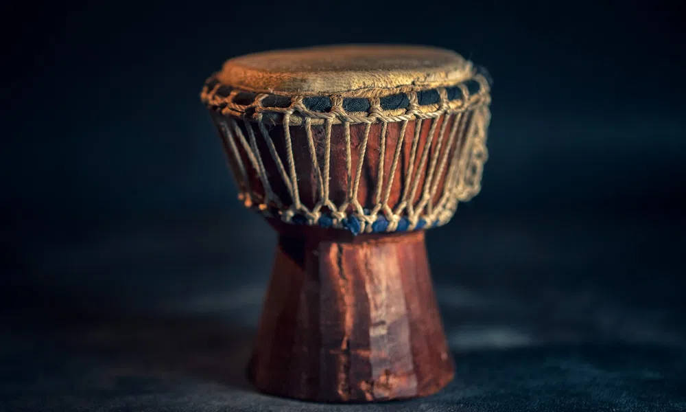 Close-up of a traditional wooden drum with rope tensioning on a dark background