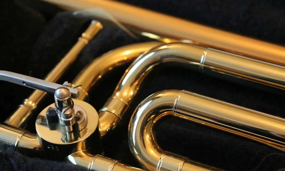 Close-up of shiny brass trumpet valves and tubing on a black fabric background with reflective golden finish