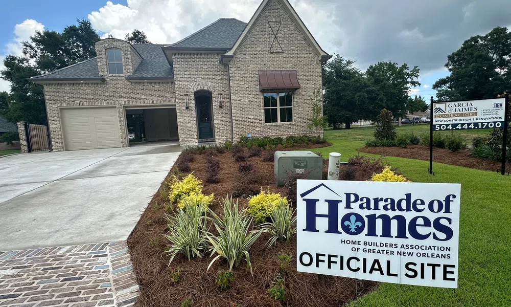 New brick home with landscaping and Parade of Homes official site sign in front yard under cloudy sky.