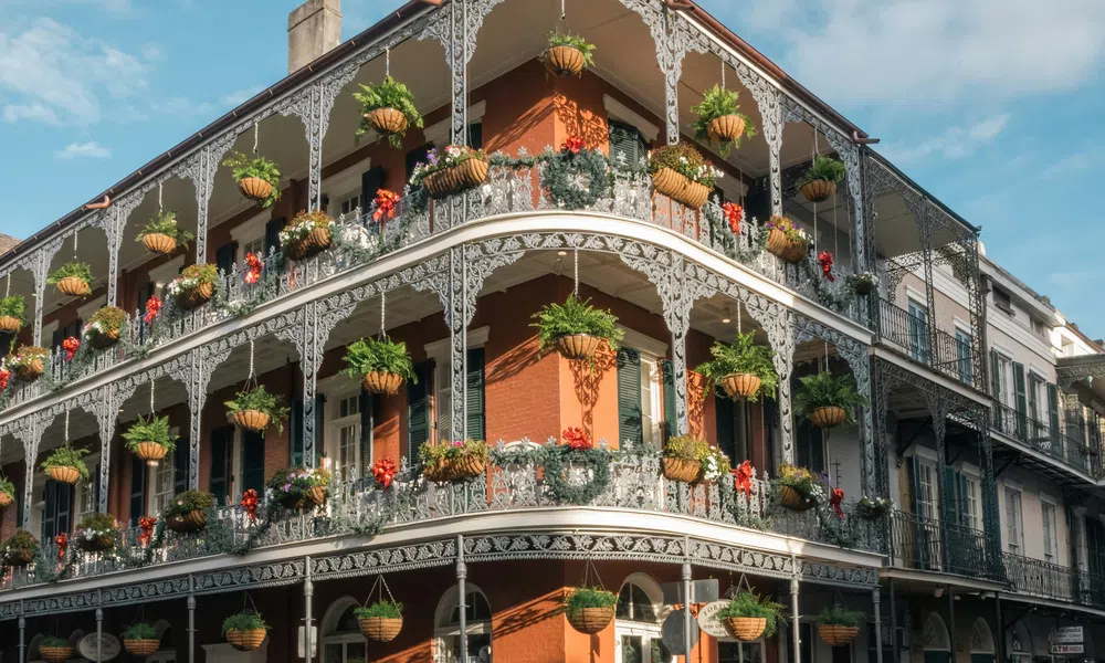 Historic building with ornate iron balconies adorned with hanging flower pots in French Quarter, New Orleans.