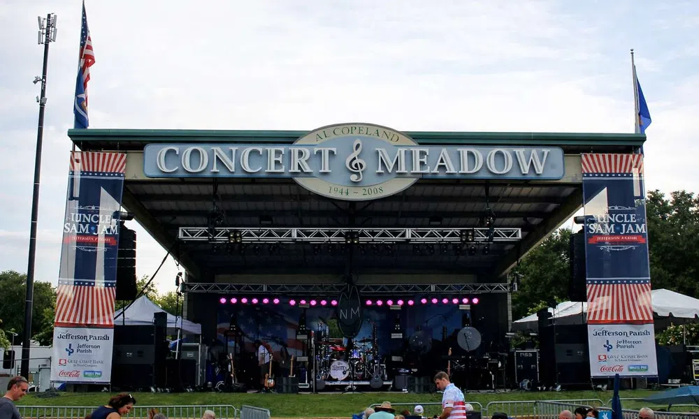 Outdoor stage setup at Al Copeland Concert & Meadow with banners for Uncle Sam Jam event and audience seating.