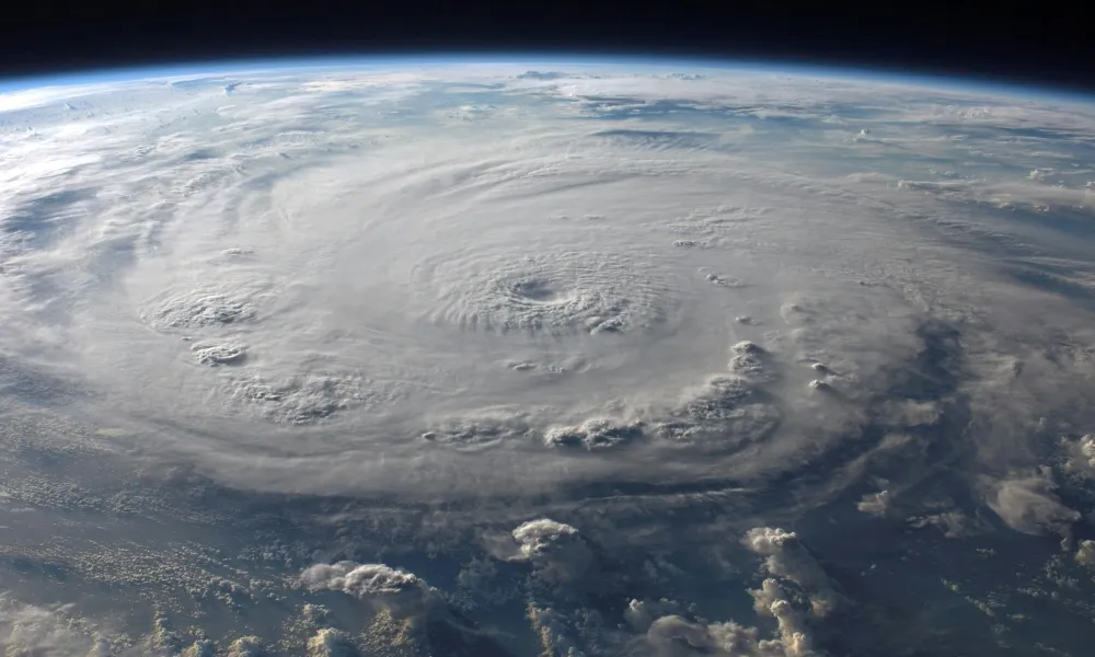 Satellite view of a massive hurricane swirling over the Earth's ocean surface under the atmosphere.