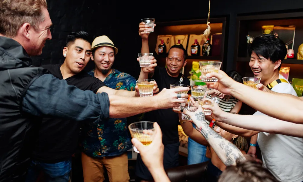 Group of friends raising glasses together in a cheerful toast at a cozy indoor gathering.