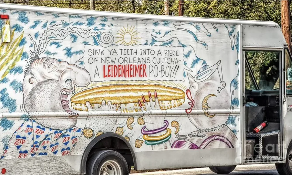 Truck mural featuring a man about to eat a large po-boy sandwich with vibrant New Orleans-themed artwork.
