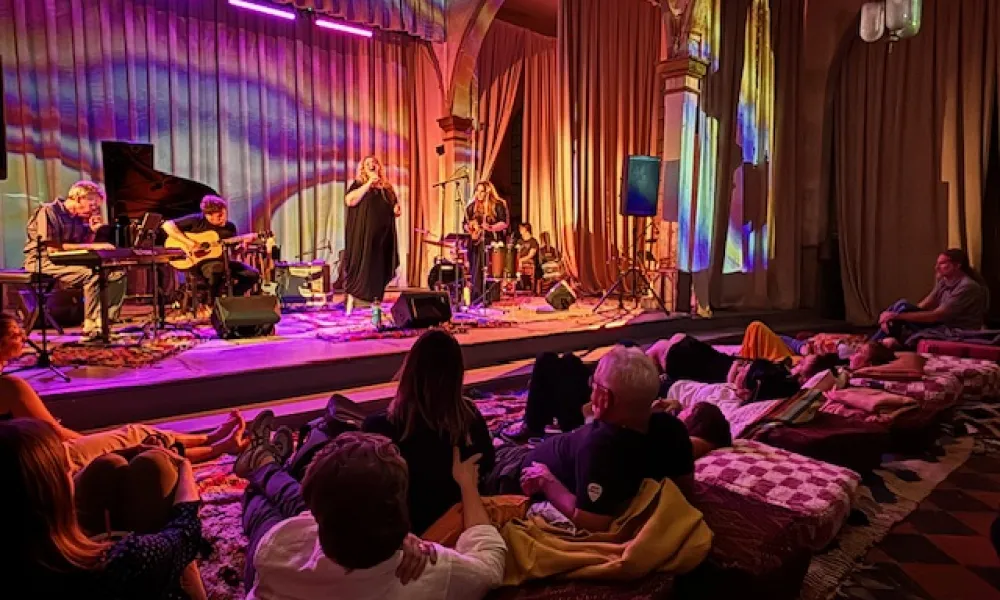 Intimate live music performance with colorful lighting and a cozy audience setting.