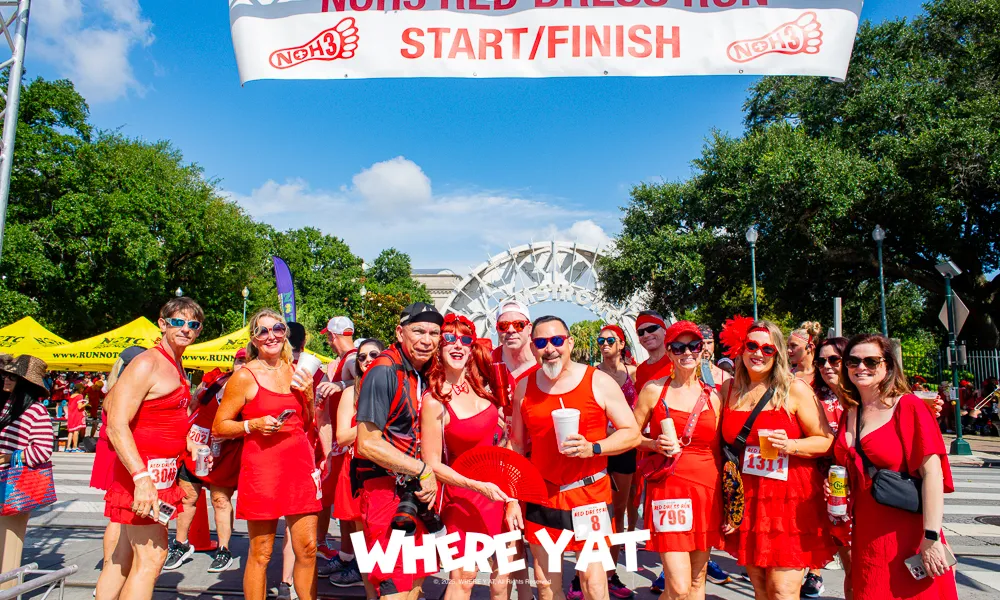 Group of people dressed in red at the NOH3 Red Dress Run start/finish line outdoors on a sunny day.