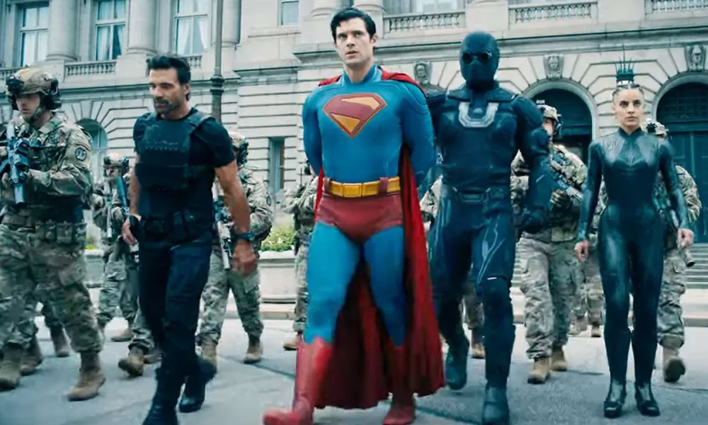 Superheroes including Superman and armed soldiers walking together in front of a classical government building.