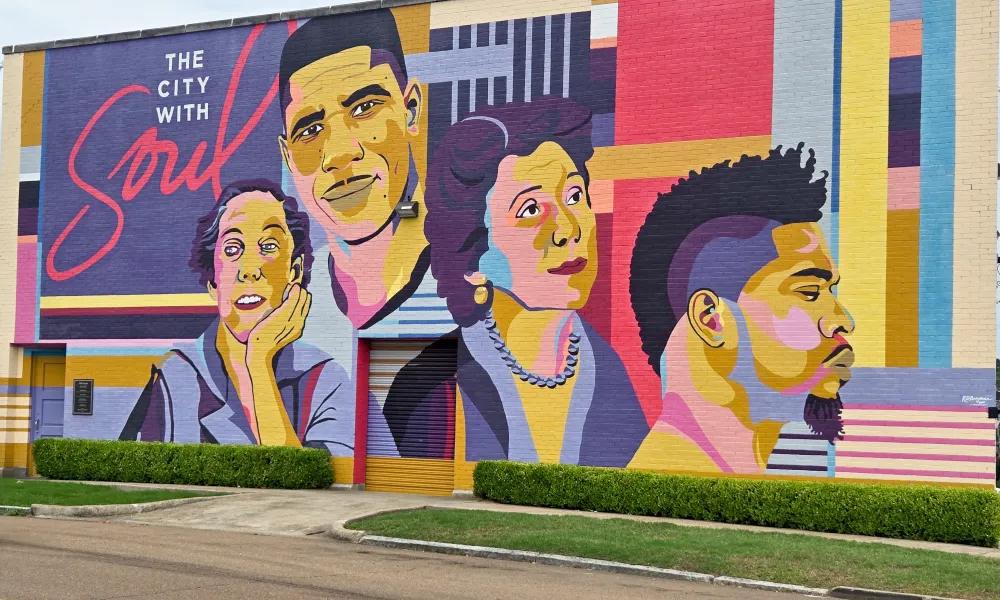 Colorful mural on a building wall depicting diverse faces with the text The City With Soul in vibrant colors.