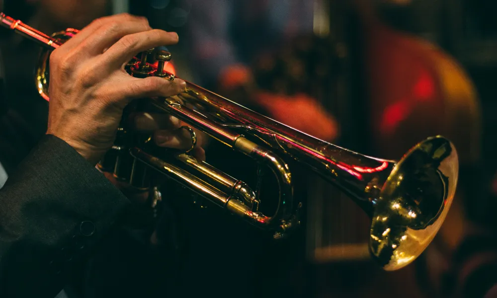 Close-up of musician playing a shiny brass trumpet in a dimly lit jazz club or concert setting