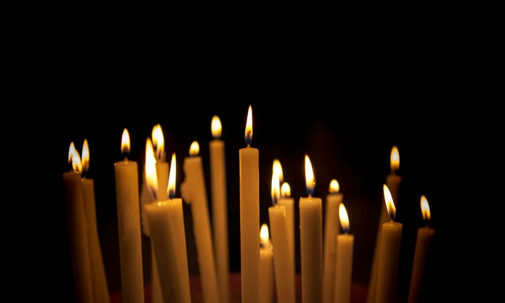 Multiple lit candles glowing against a dark background creating a warm, peaceful ambiance.