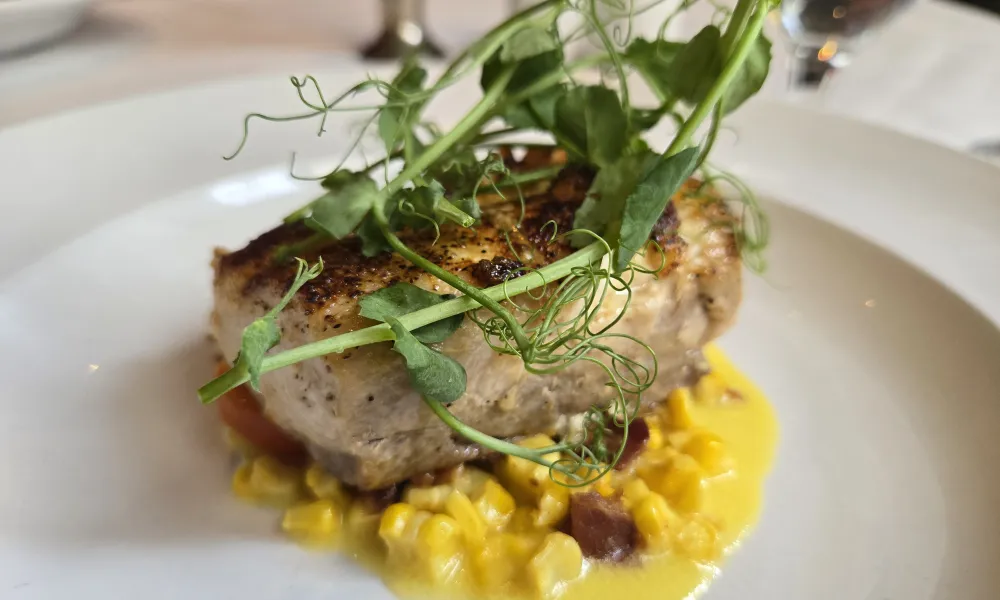 Grilled fish fillet topped with fresh pea shoots served on creamy corn sauce with bits of bacon.