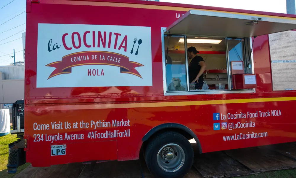 Red La Cocinita food truck parked with open service window and contact info at Pythian Market New Orleans