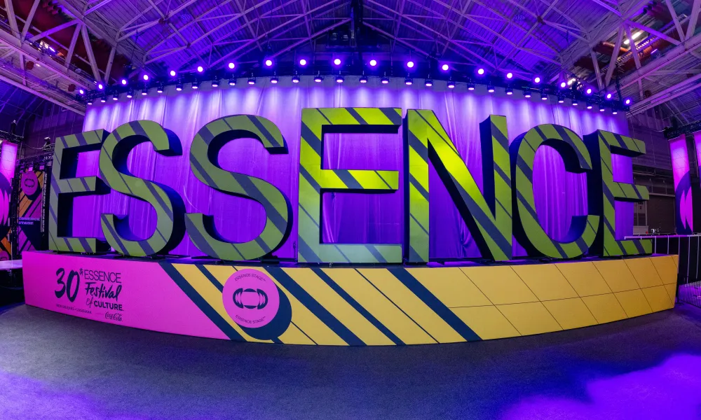 Large 3D letters spelling ESSENCE at the 30th Essence Festival with purple lighting in a convention hall.
