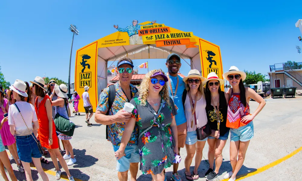 Group of friends enjoying the New Orleans Jazz & Heritage Festival on a sunny day.