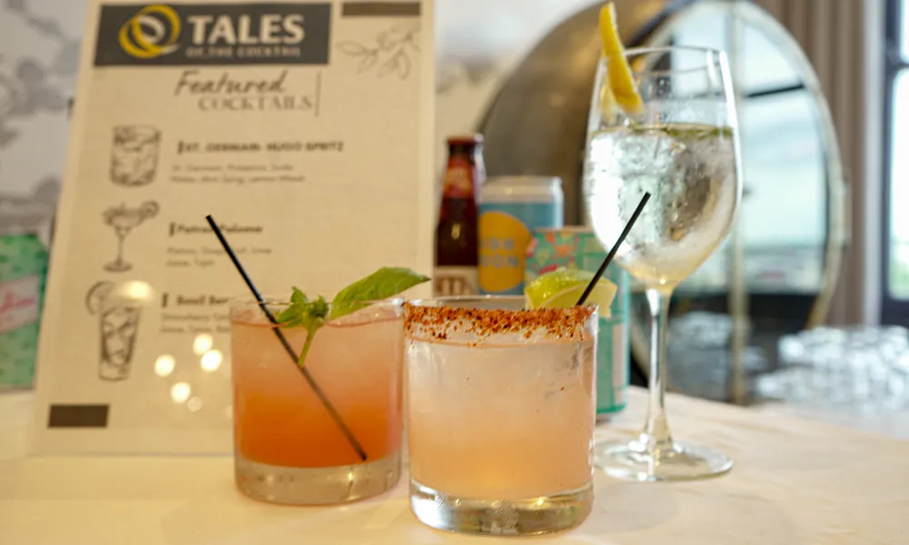 Three cocktails on a table with a menu in the background at Tales on the Crescent bar