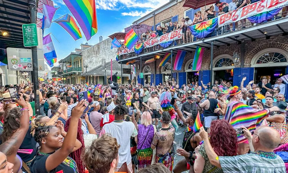 Crowd celebrating at a vibrant Pride parade with rainbow flags, colorful outfits, and lively street atmosphere.