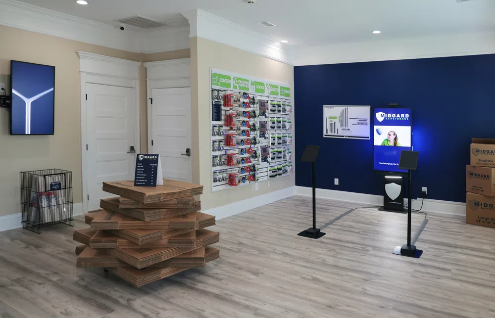 Modern storage facility office with samples, digital screens, and packing supplies on light wood flooring.