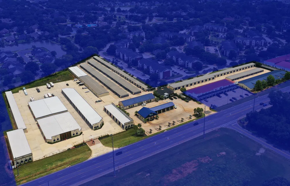Aerial view of a large self-storage facility with multiple storage buildings and parking areas near a main road.