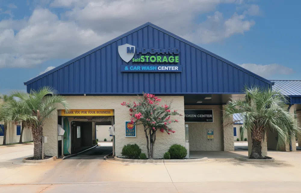 Midgard Self Storage and Car Wash Center building with palm trees and clear sky in front.