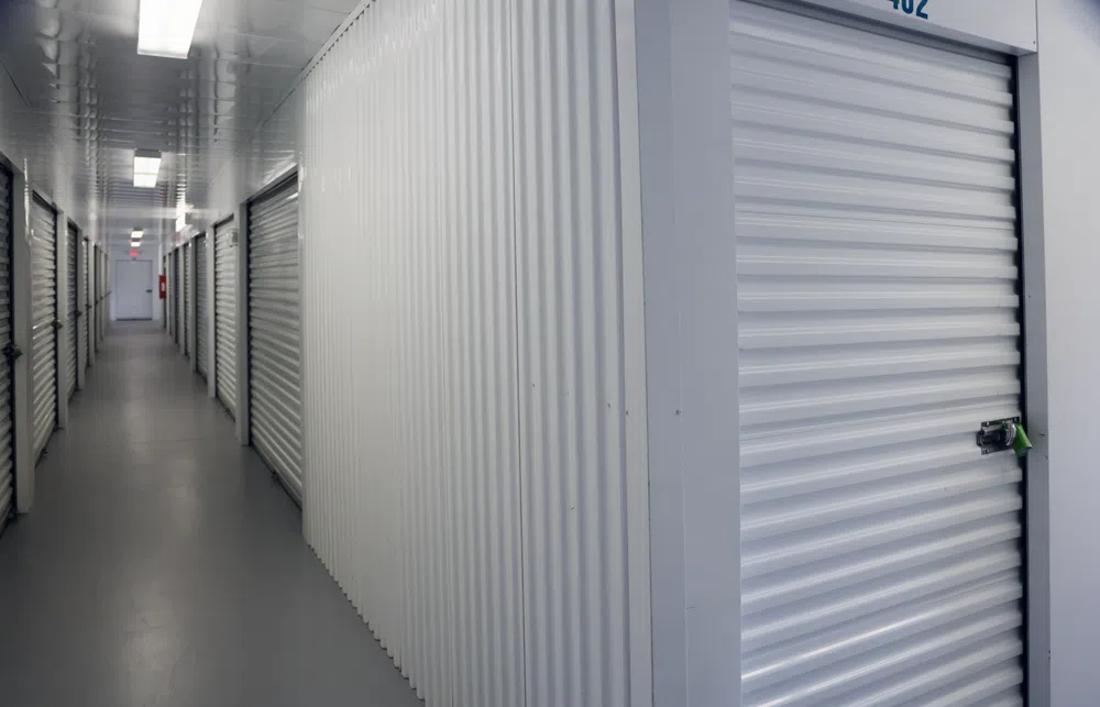 Interior hallway of a self-storage facility with rows of white metal storage unit doors and overhead lighting.