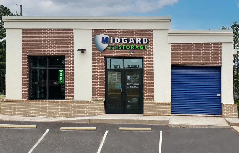 Midgard Self Storage building with brick facade, glass door, blue storage door, and parking spaces outside.