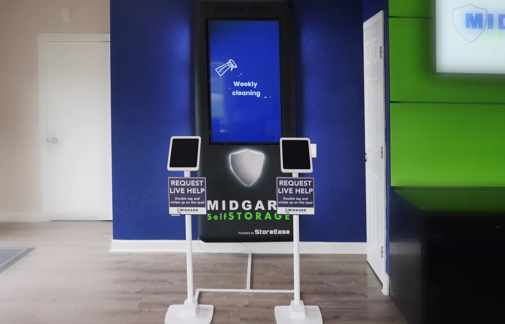 Midgard Self Storage help kiosks with touchscreens in a modern reception area with blue and green walls.