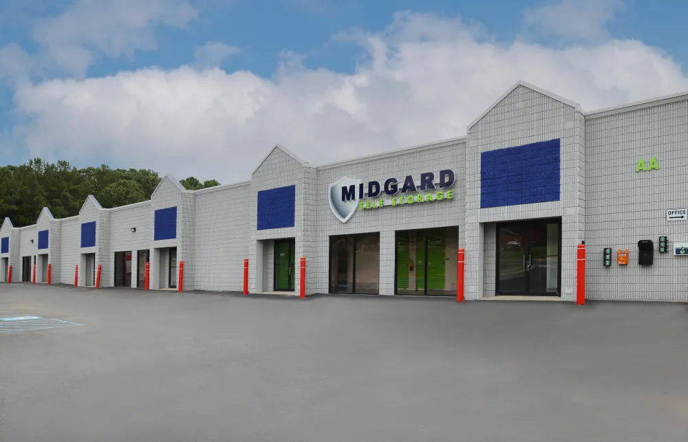 Exterior view of Midgard self storage facility with gray walls and blue accents under cloudy sky.