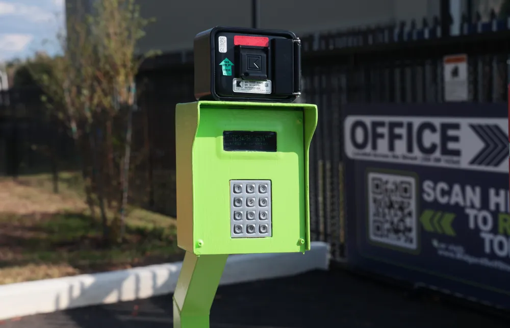 Green keypad entry system with black card reader at the entrance of a facility near an office sign.