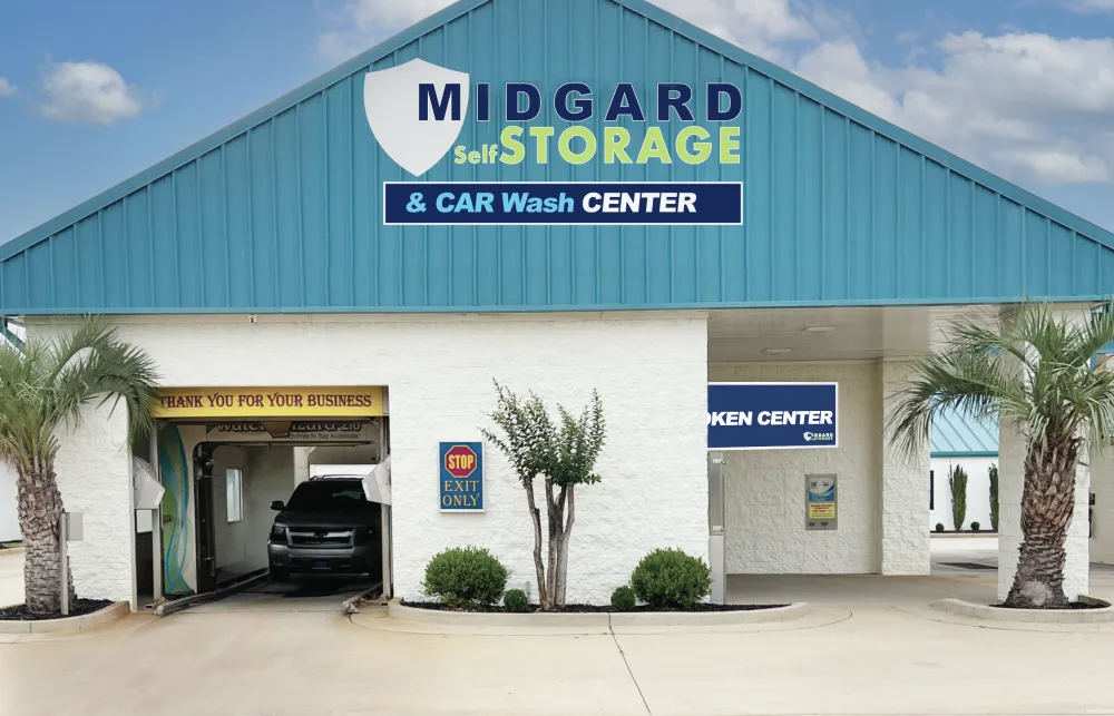 Midgard Self Storage and Car Wash Center building with drive-through car wash bay and palm trees under blue sky.