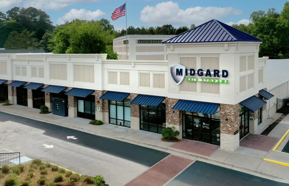 Modern Midgard Self Storage building with blue awnings, brick accents, and American flag on a sunny day.
