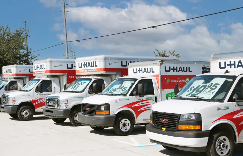 Row of U-Haul rental trucks parked outdoors under a partly cloudy sky, ready for moving service.