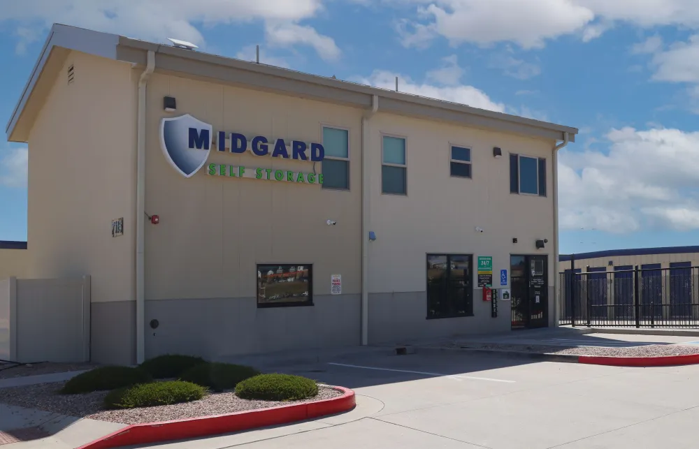 Midgard Self Storage facility building with signage under blue sky and parking area in front.