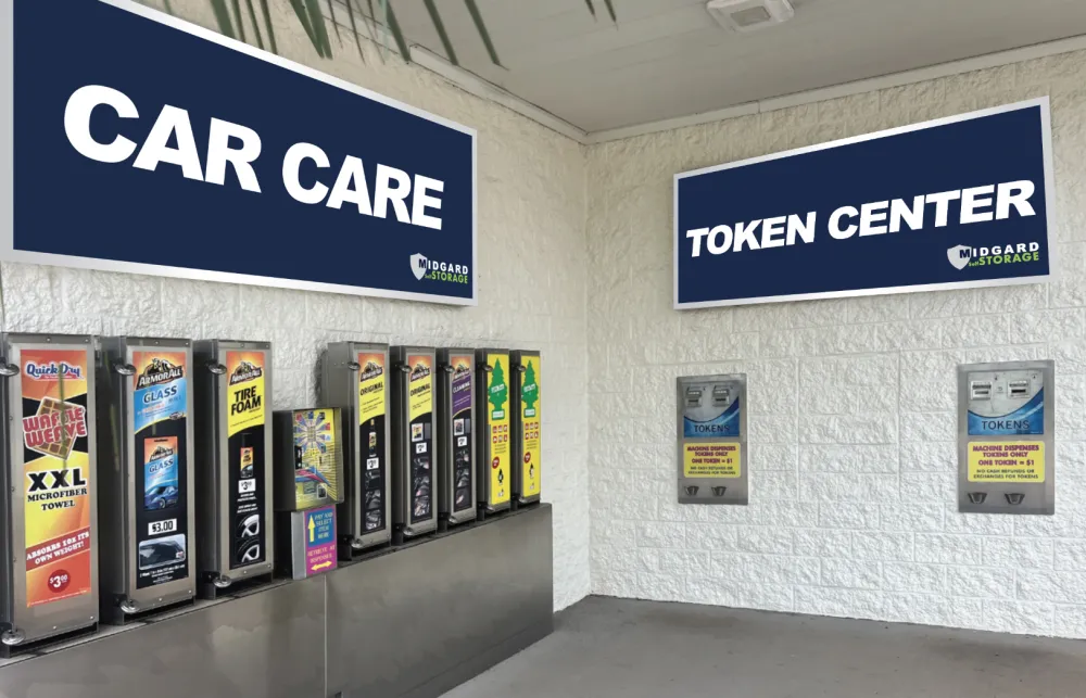 Car care product dispensers and token machines under Car Care and Token Center signs at self-storage facility.
