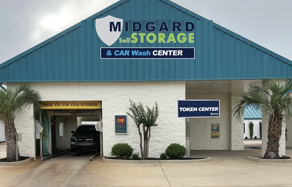 Midgard Self Storage and Car Wash Center building with a car exiting the wash under cloudy sky.